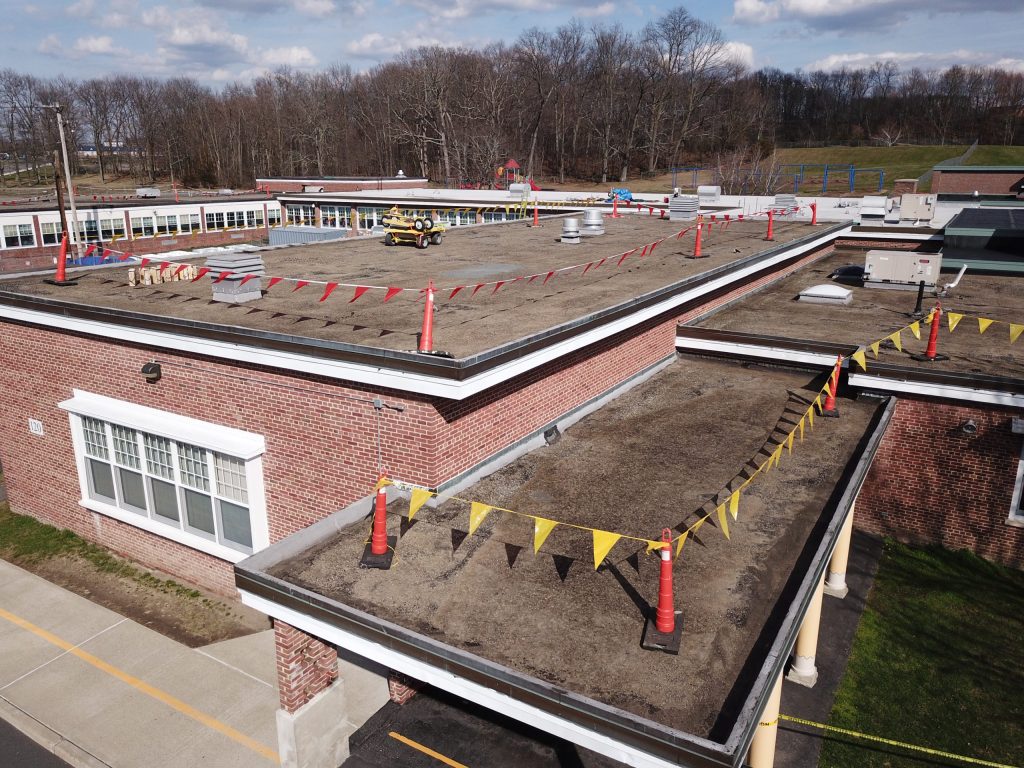 A flat roof on top of a brick building has flags roped around the edges.