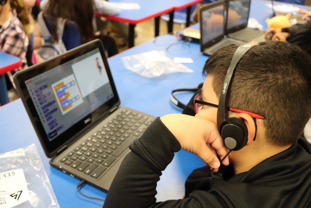 An elementary school student wears headphones and works on a Chromebook during the last session of the Coding Club at Goshen Intermediate School.