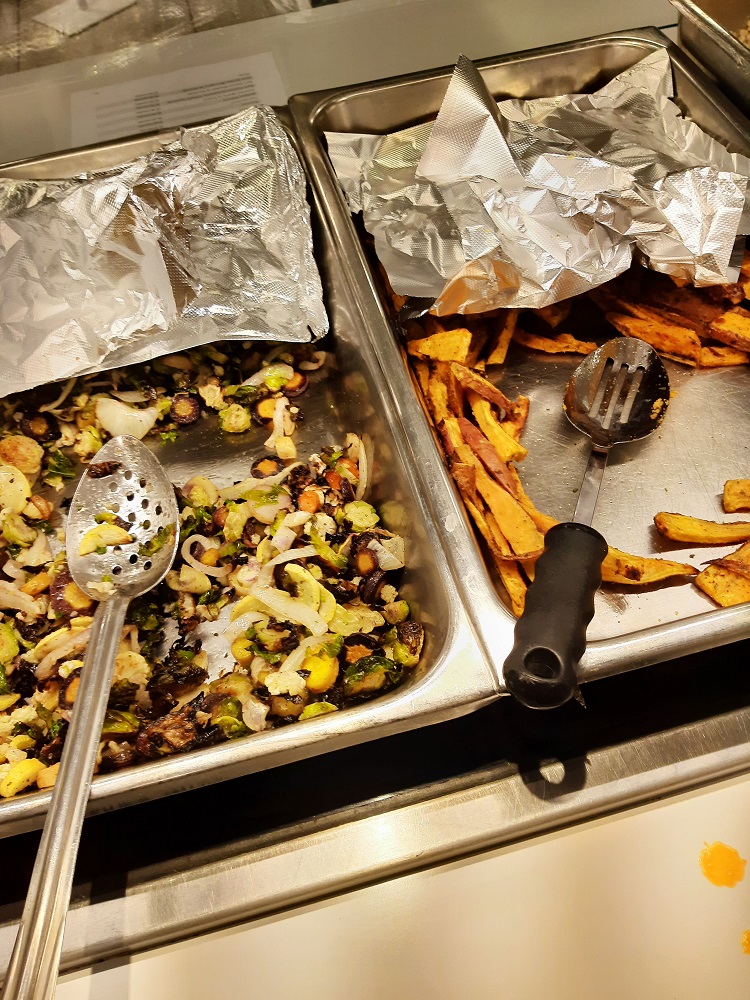 Roasted vegetables rest in trays covered in aluminum foil.