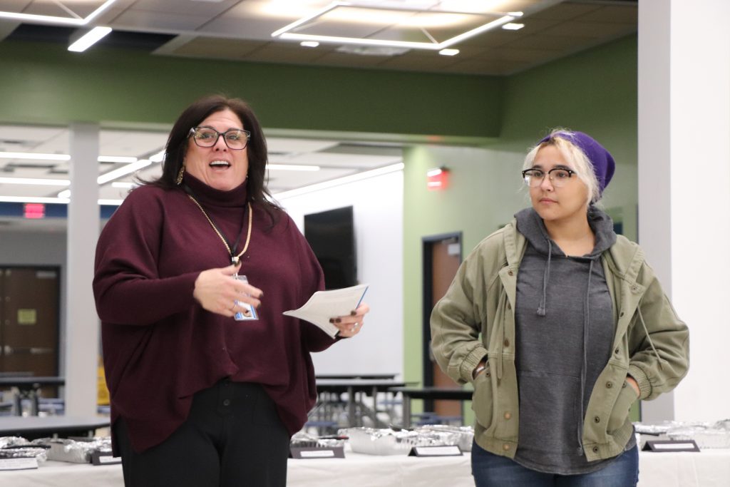 A teacher and a high school student stand together as the teacher explains why the student is deserving of the Goshen Greats nomination for Q1 of the 2023-24 school year.