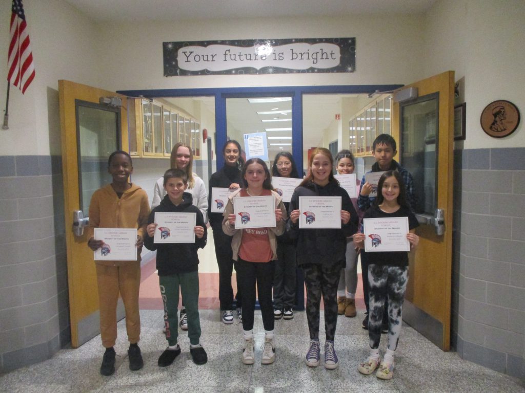 Middle school students hold certificates and stand together in a hallway as a group in front of a sign that says "Your future is bright."