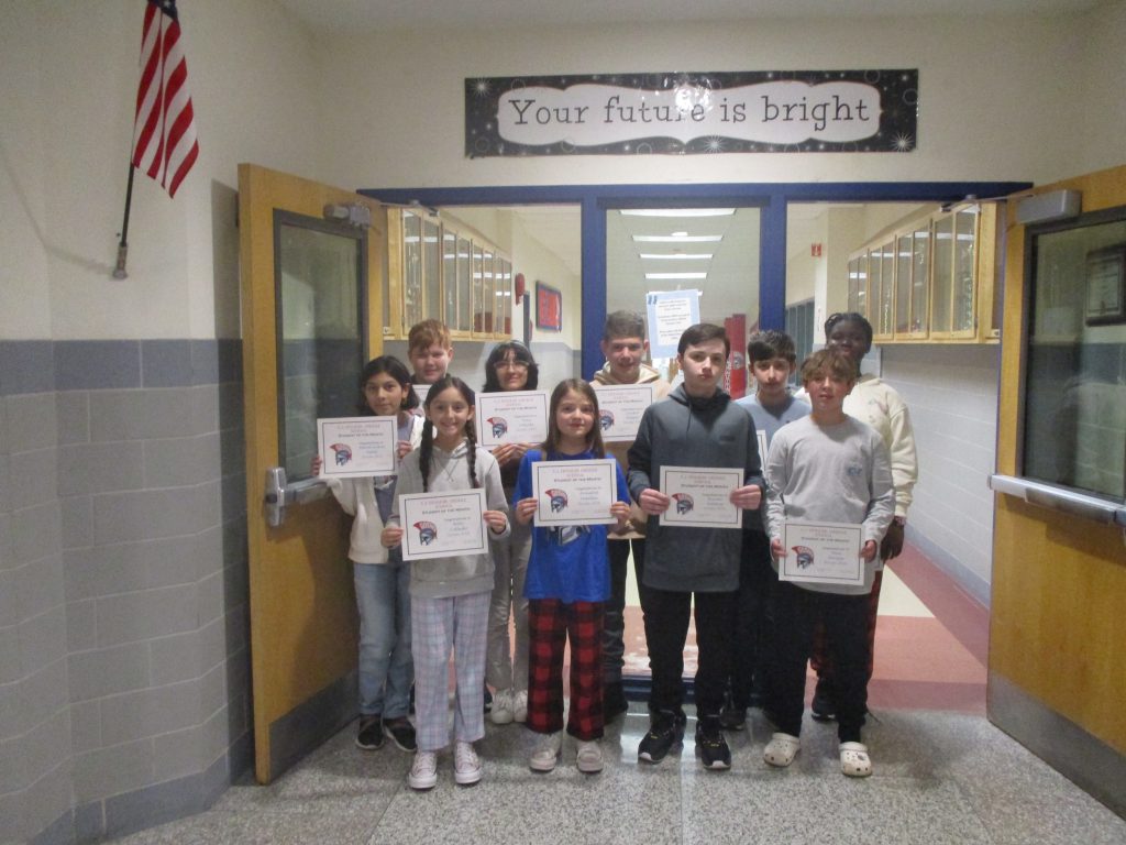 A group of middle school students holding certificates stand together in a hallway in front of a sign that says "Your future is bright."