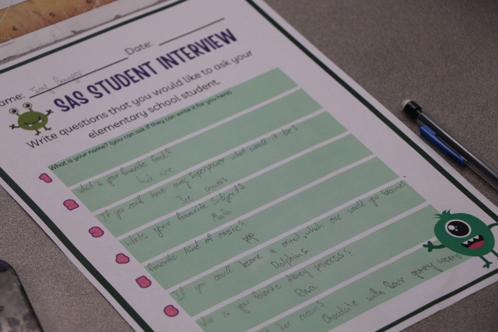 A picture of a worksheet that says "SAS Student Interview" with text that reads "What is your favorite food? Fried rice," "If you could have any superpower, what would it be? Ice powers," "What is your favorite subject? Math," "Favorite kind of music? Pop," and more.