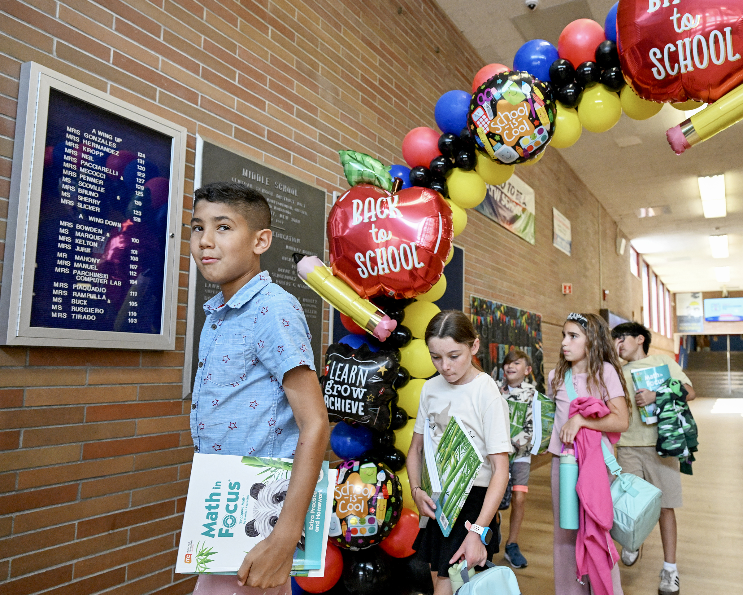 Students walk through a balloon arch in a school hallway