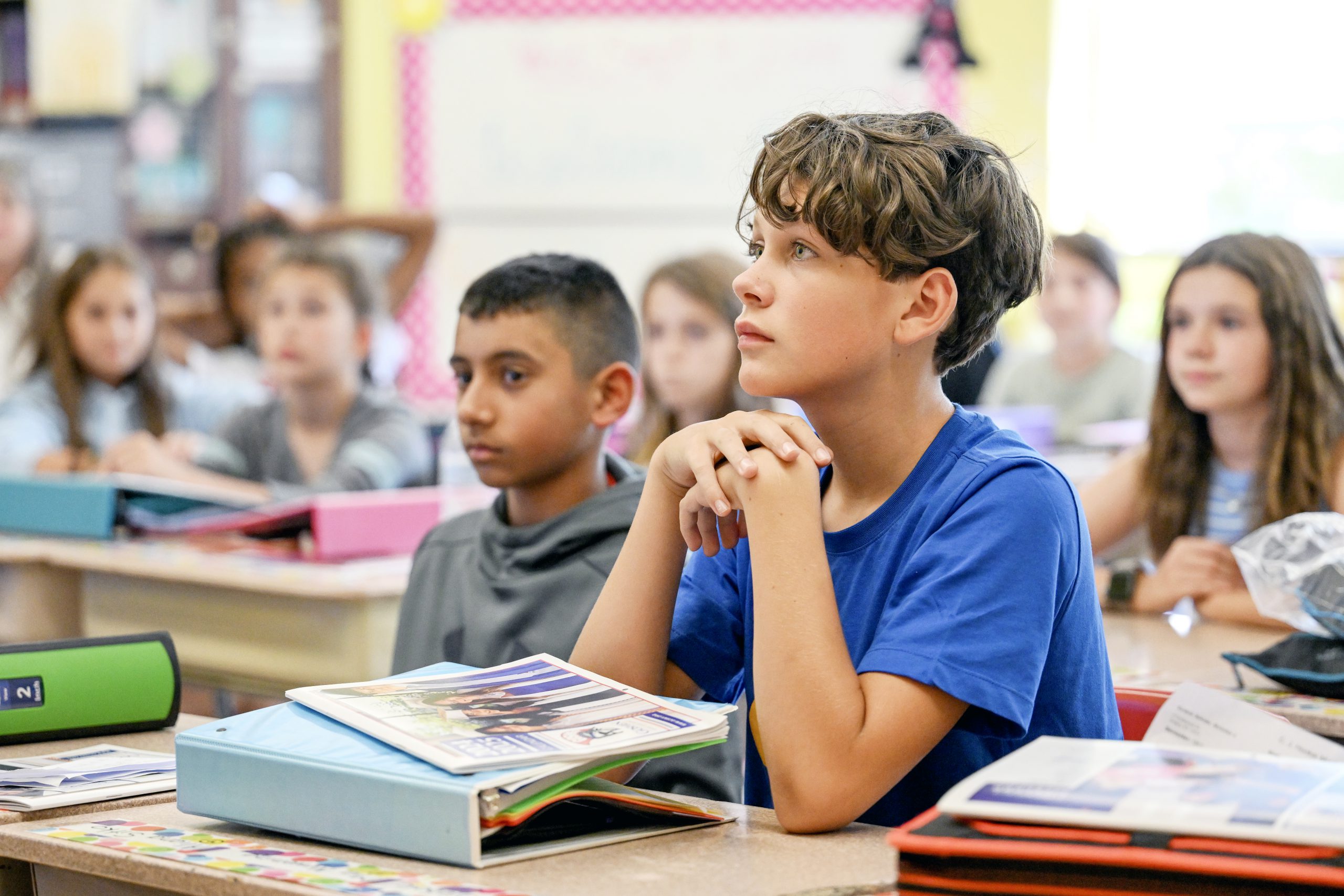 A student listens intently while siting at a desk in a classroom.