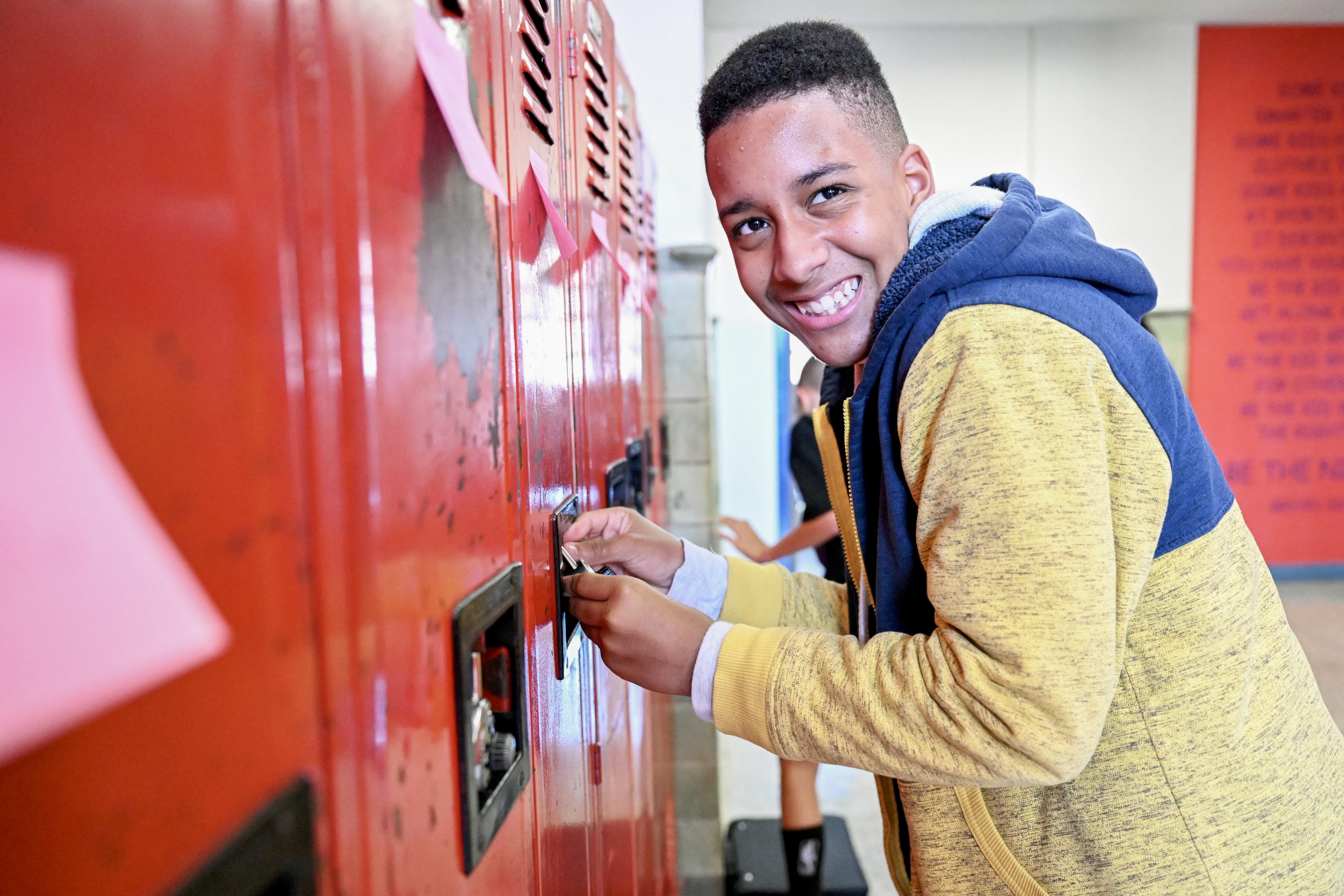 A student grins while trying to open his lock on his locker.