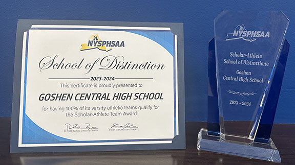 A certificate and a clear glass trophy on a desktop.