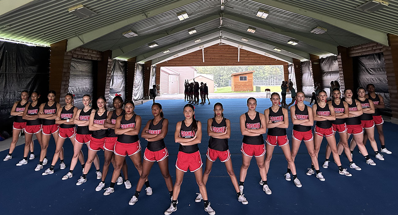 Athletes with arms crossed stand in a V 