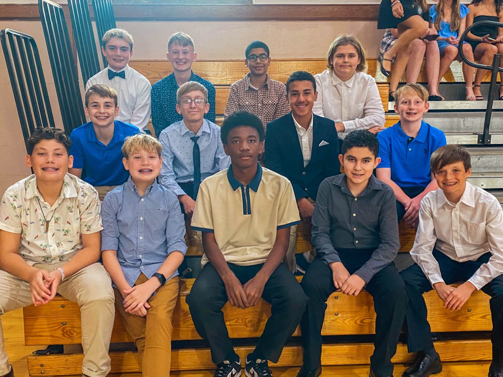 Students sit in the bleachers at the gym at the National Junior Honor Society Induction ceremony.