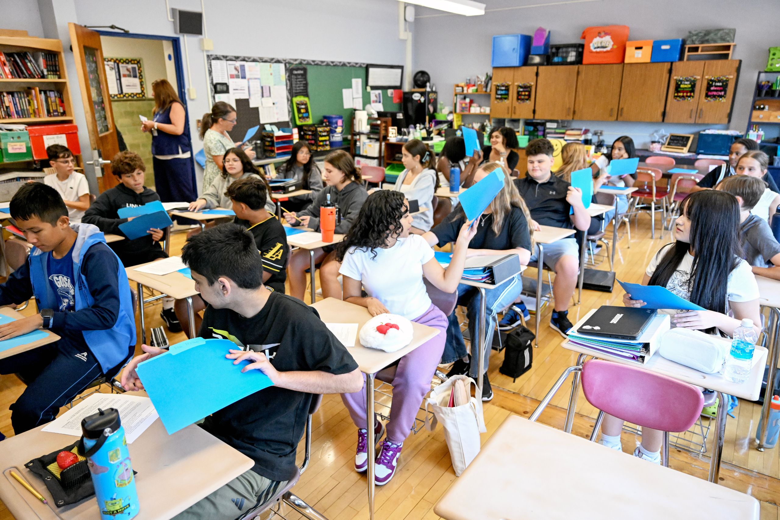 Students passing supplies behind them in rows at their desks.