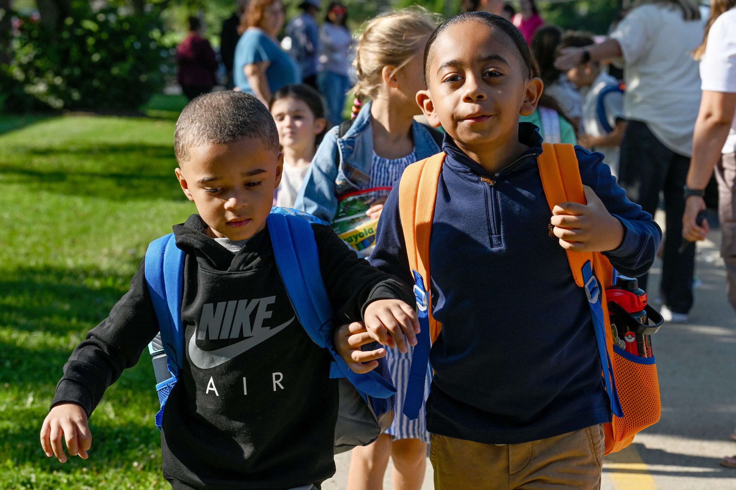 Students walk into school after getting off the bus at the first day of school.