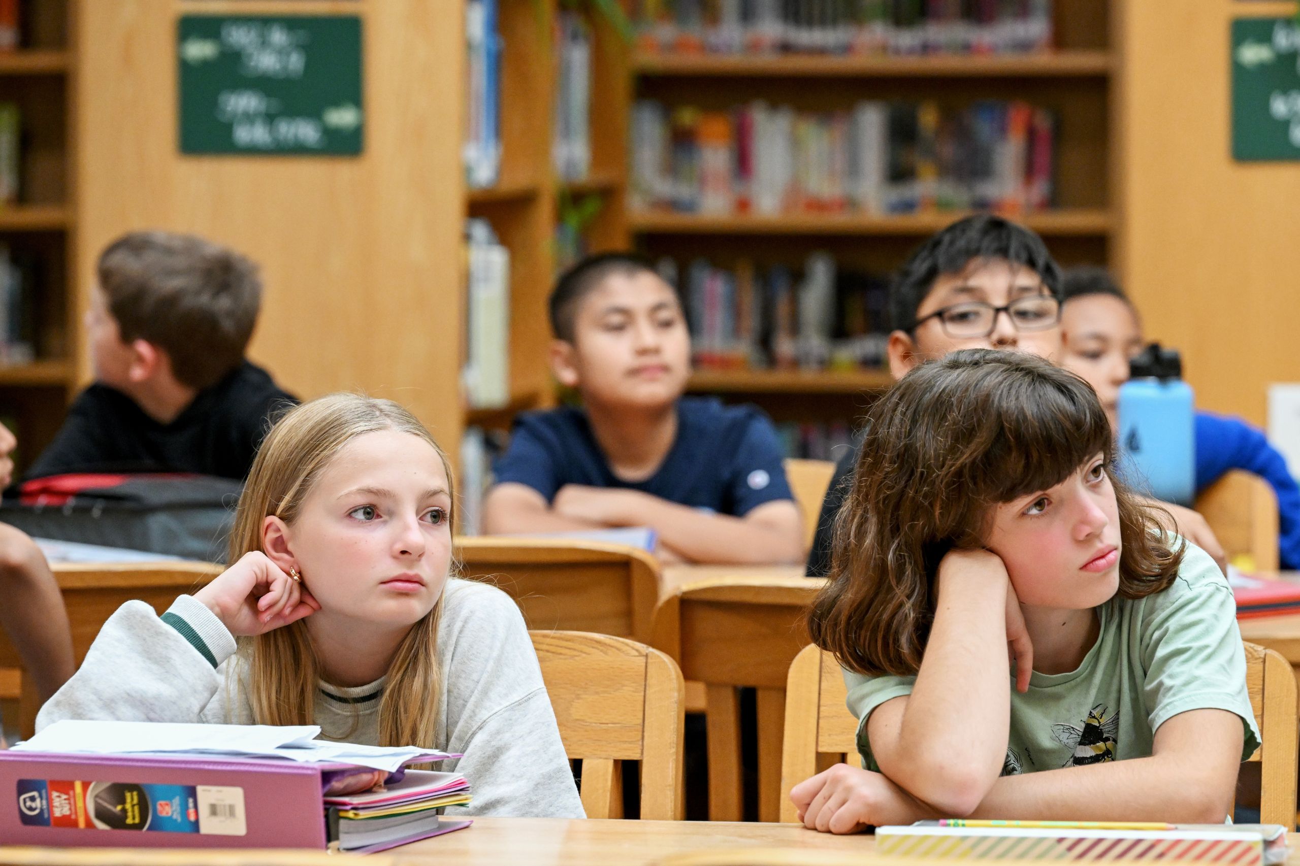 Students sit in the library and pay attention to a speaker.