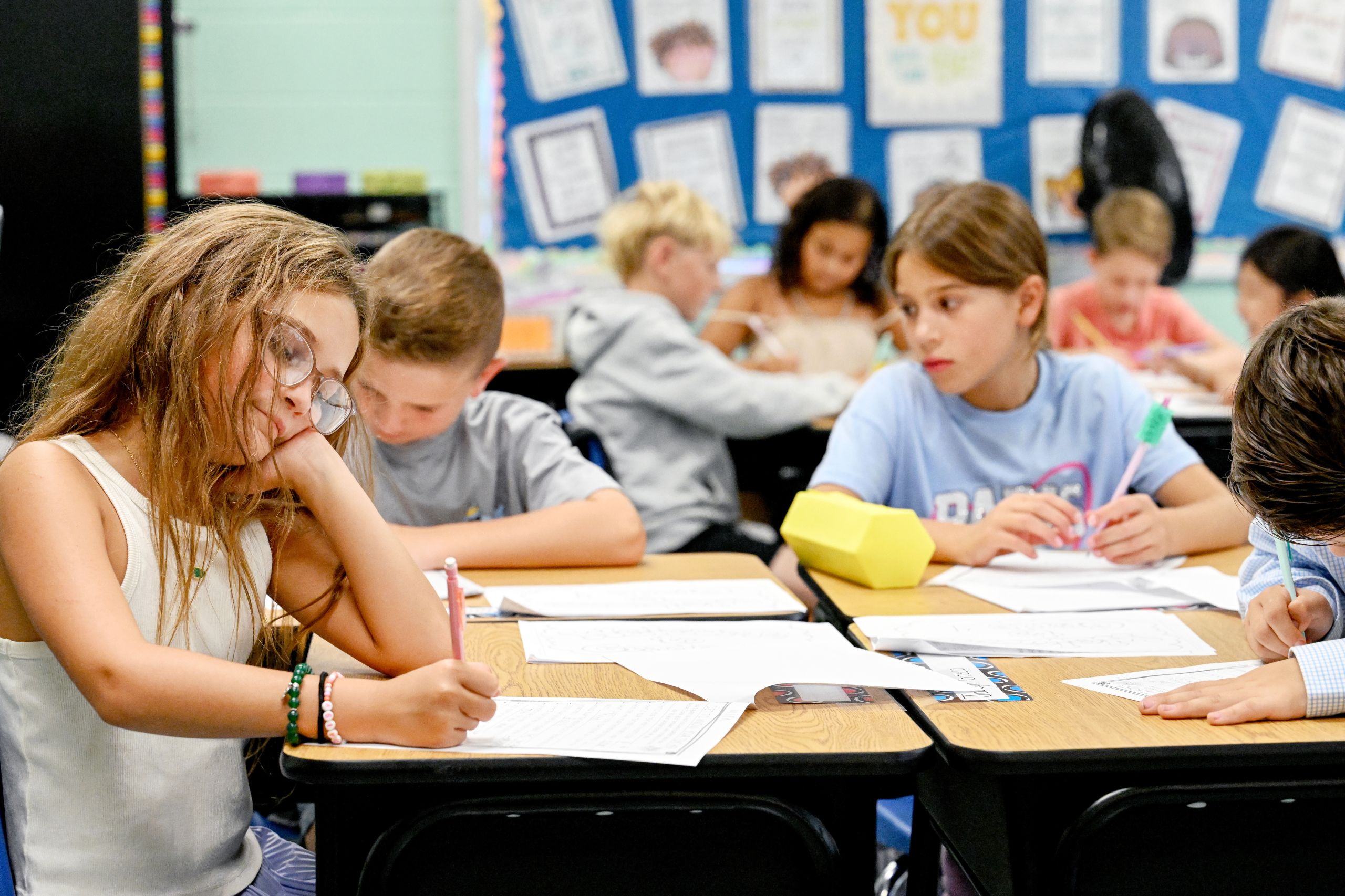 A table of students sit and complete their classwork. 