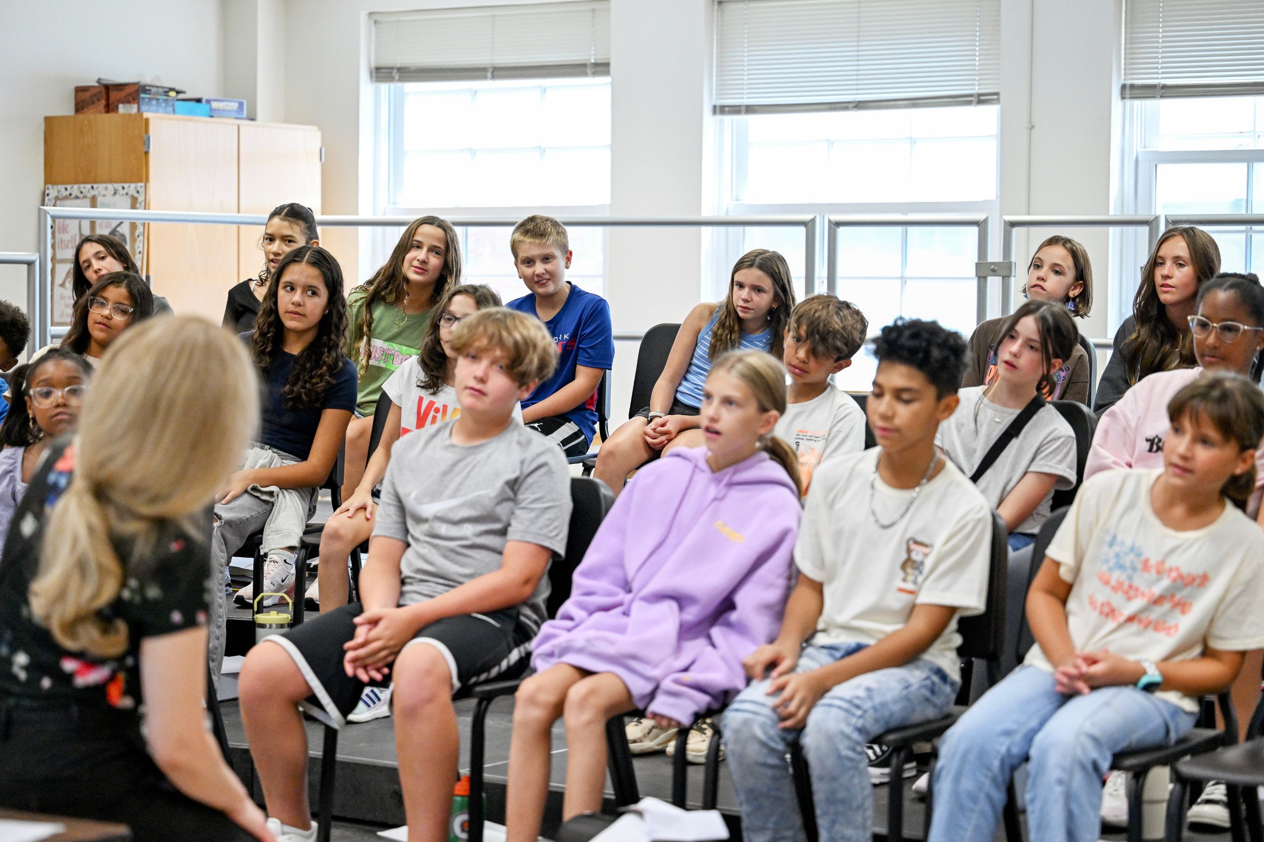 Students lean in their chairs to one side and sing in a music class