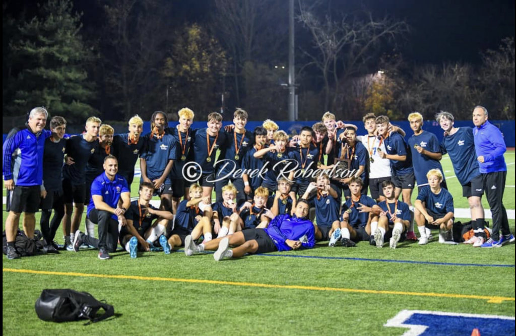 The Goshen Boys soccer team poses on the field with Section 9 championship medals following their victory.