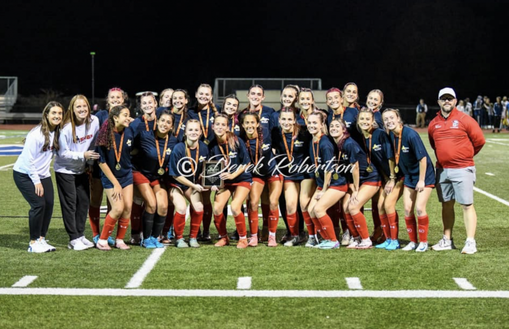 The Goshen Girls soccer team poses on the field with Section 9 championship medals following their victory.