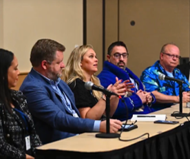 Dr. Matthew Wentworth sits at a table with panelists during the  “AI for School Leaders - Focus on the Opportunities” discussion. 