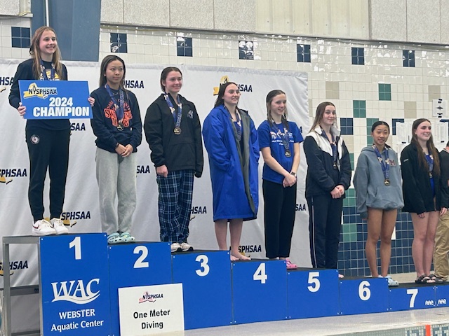 Kaylee Croughan stands on the fifth place spot on the podium with the top divers in the state all posing for photos at the NYSPHAA swimming and diving championship. 