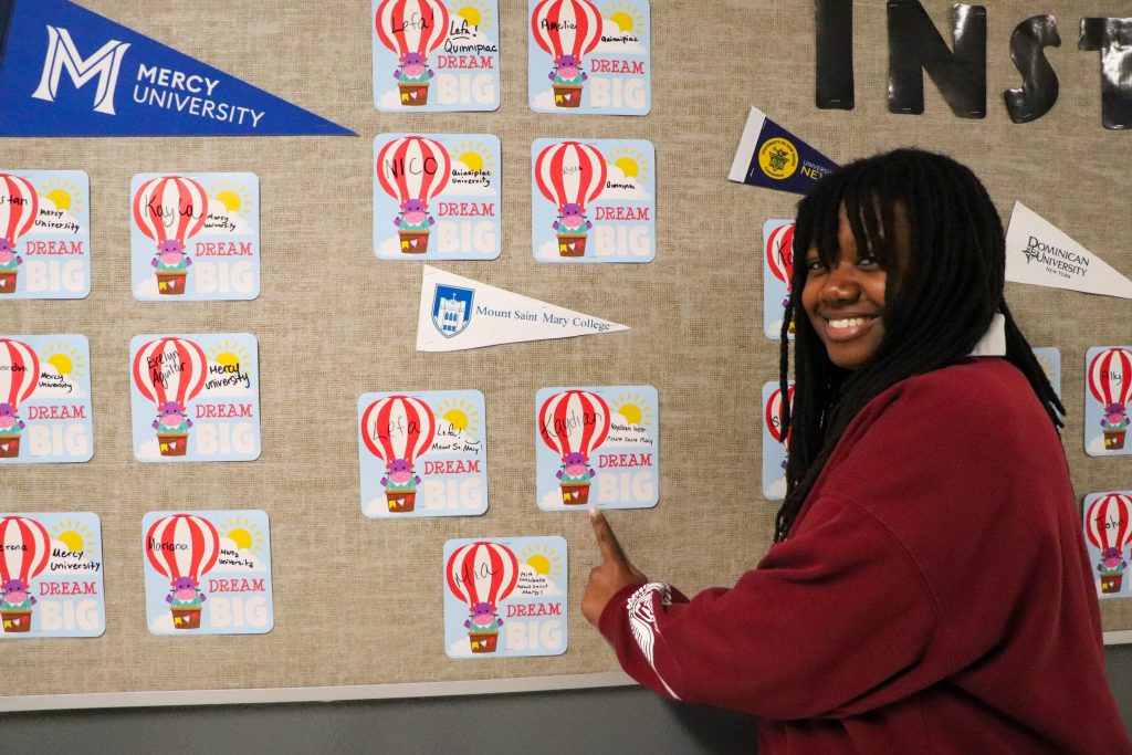 A student stands near her name under an "Mount Saint Mary" banner on the wall at the instant admissions board in the hallway at Goshen High School. 