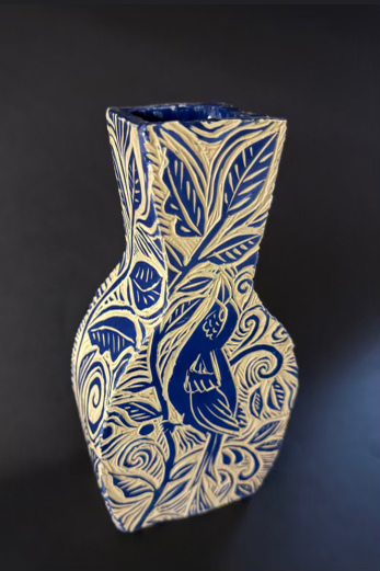 A vase made by a student. The vase is blue and white with a bird and flowers on it. 