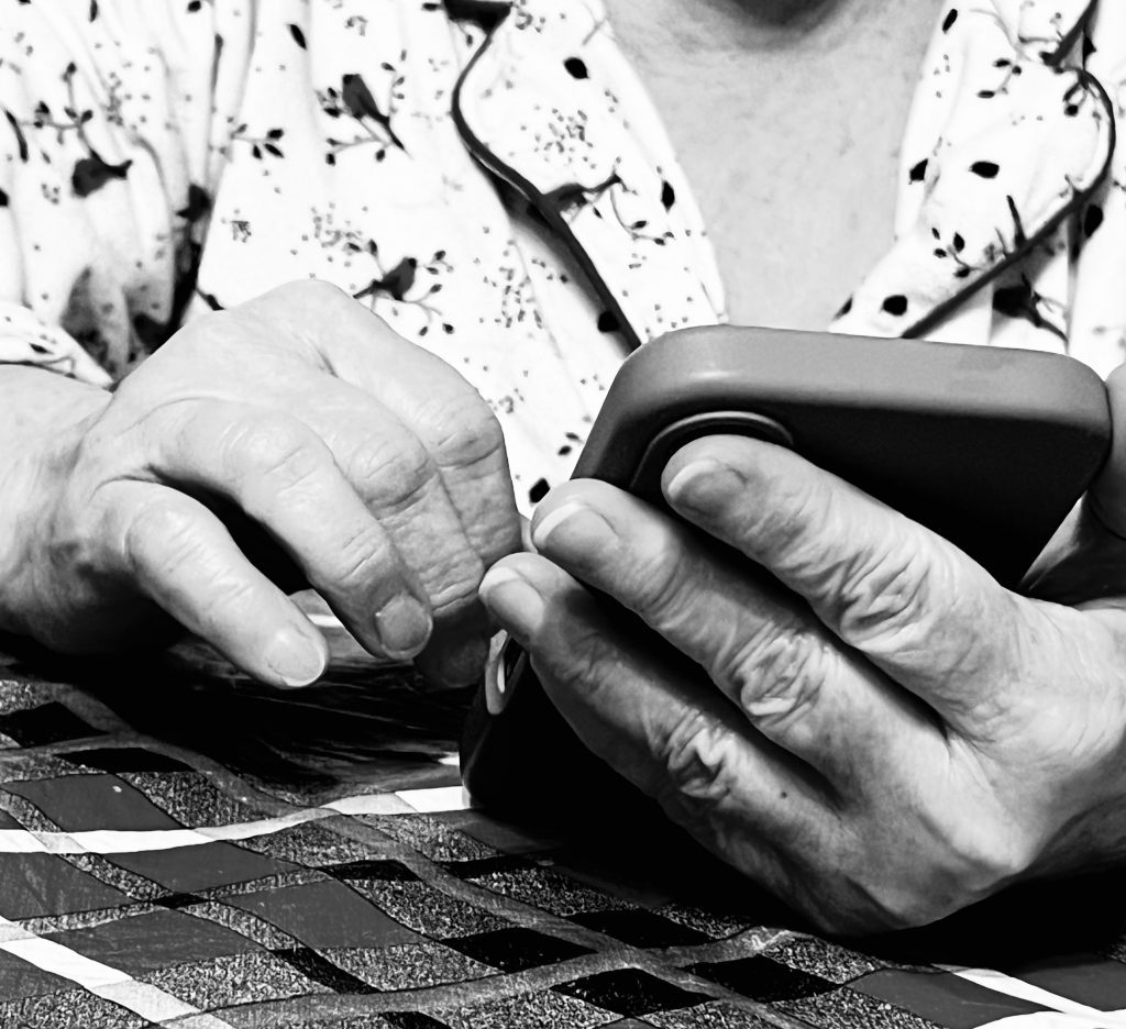 A person scrolls through their phone, the photo is taken from table level is black and white.