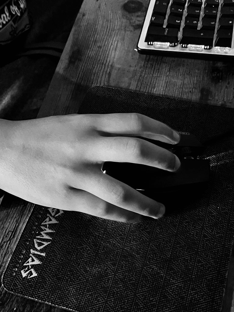 A hand is using a mouse, a keyboard is visible. The photo is black and white.