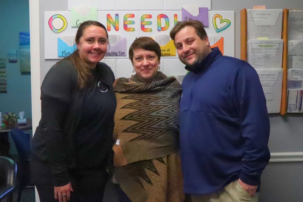 The three guidance counselors at C.J. Hooker Middle School are smiling for the camera in front of a wall with resources for students. 