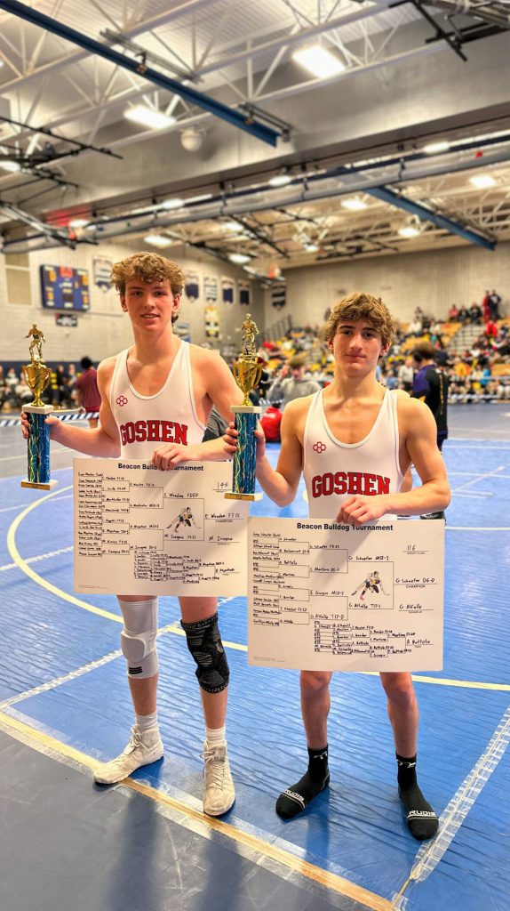 Evan Weeden and Greg Schaefer stand together and hold trophies in Goshen uniforms. They also hold brackets that show their names as the champion at the Beacon Bulldog Tournament. 