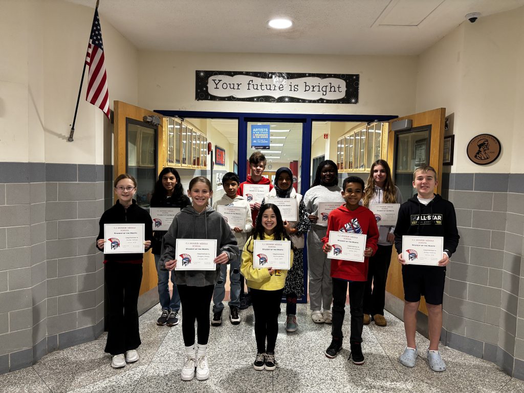 The CJ Hooker Students of the Month stand in the hallway with their certificates and smiles. They are under a sign that says "Your future is bright." 